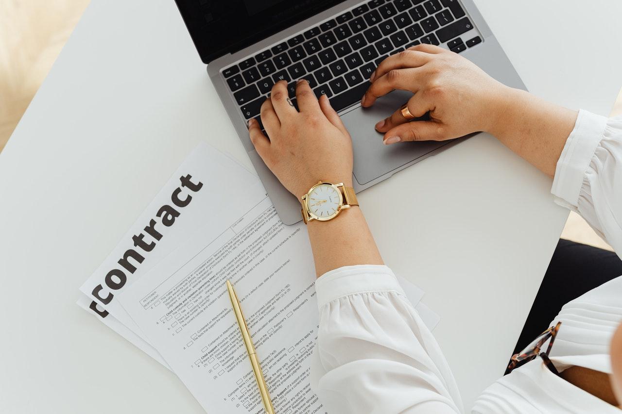 image shows hands typing secure contract on computer