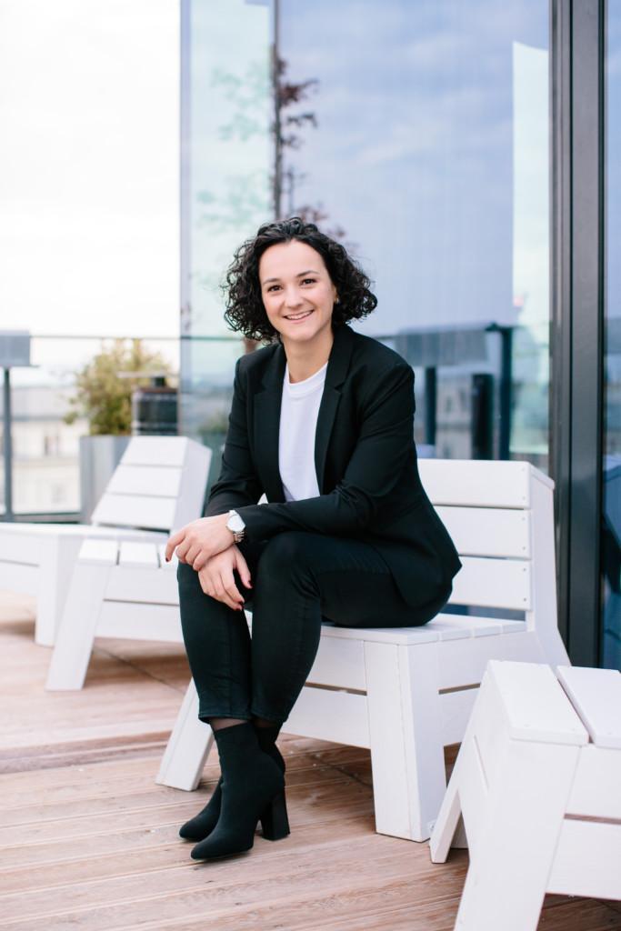 Fiona sitting on a white chair placed on a balcony smiling