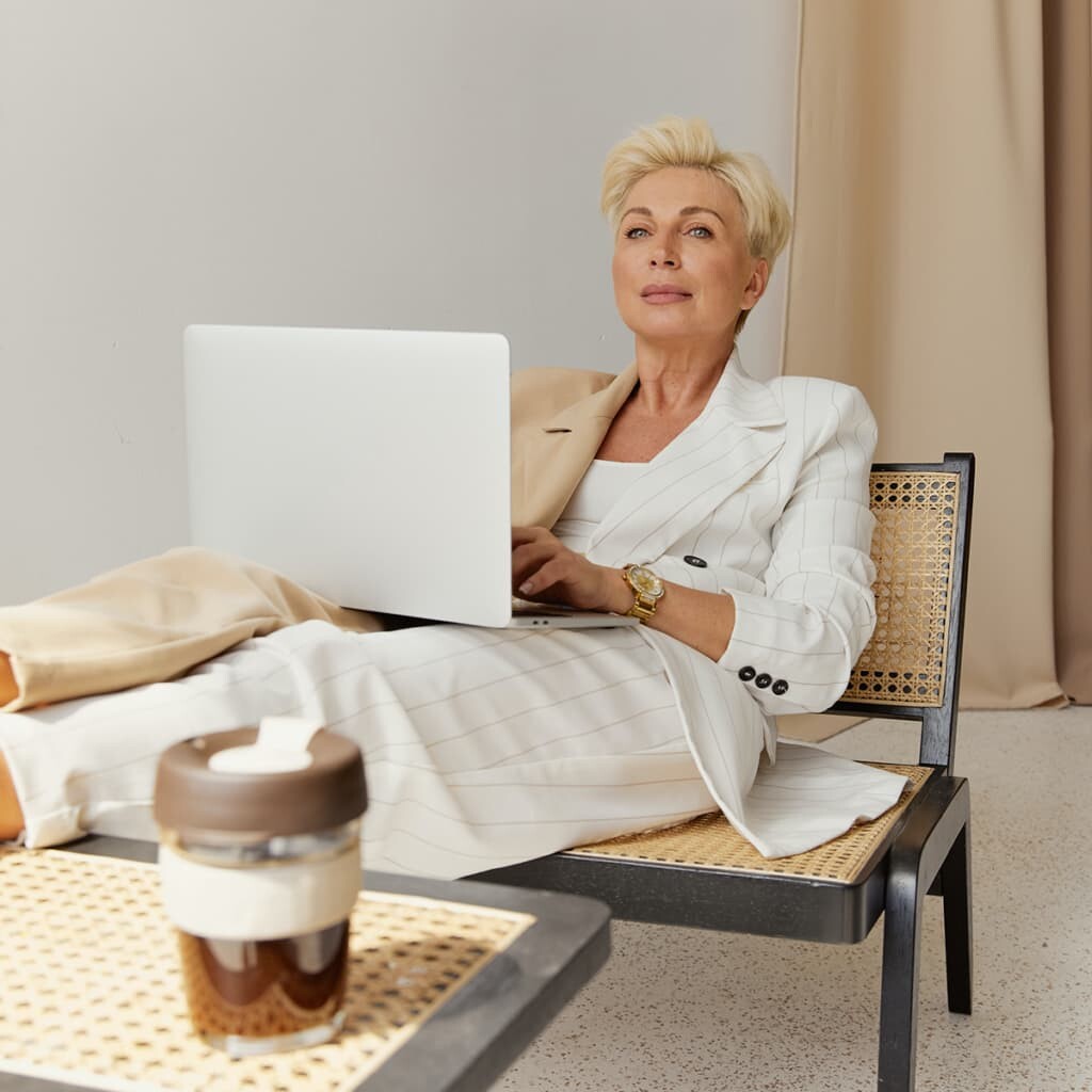 person in white sitting with laptop